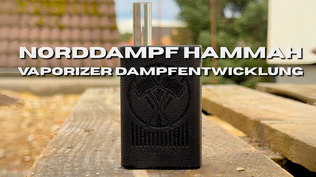 Ein schwarzer Vaporizer mit Glas-Mundstück steht auf einem Holztisch im Freien. Im Hintergrund sind Bäume und Hausdächer zu sehen.