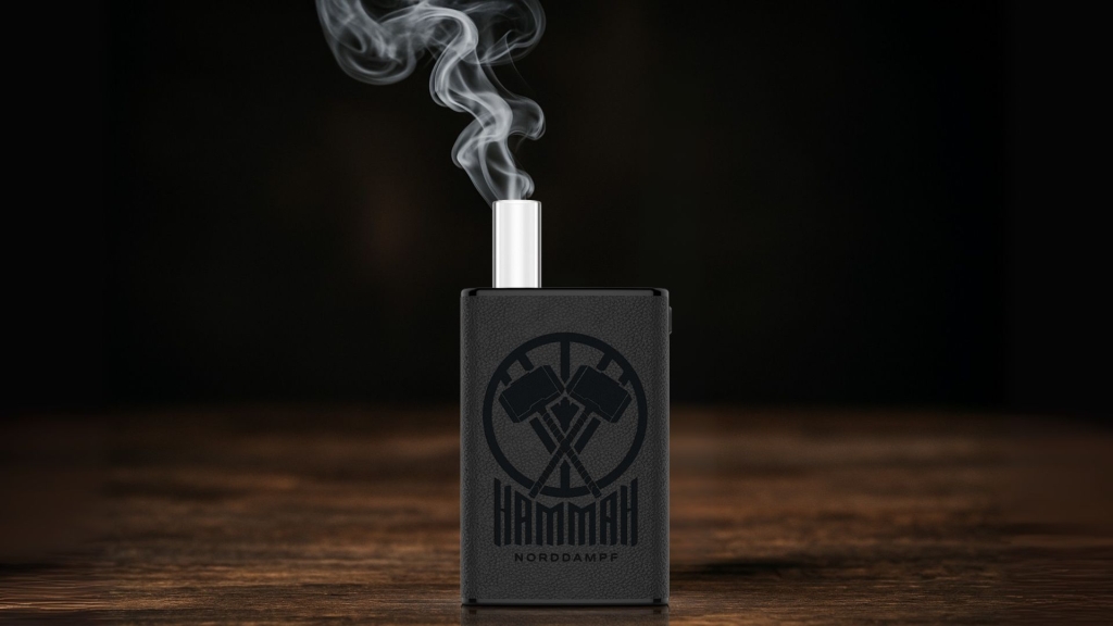 Ein schwarzer Norddampf Hammah-Vaporizer steht auf einem dunklen Holztisch, aus dem Mundstück steigt sichtbar Dampf auf, vor einem dunklen Hintergrund.